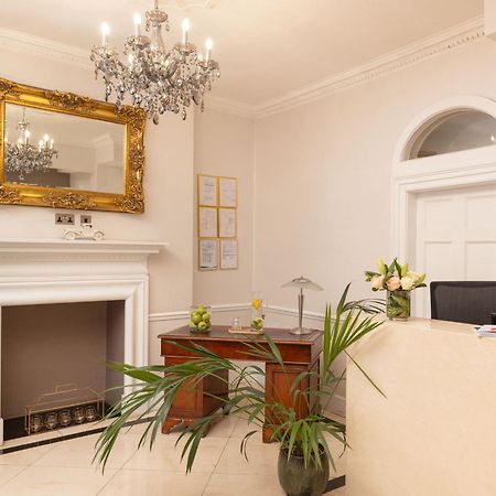 Montcalm Brewery Townhouse Hotel Londen Buitenkant foto The photo shows a stylish reception area. There is a decorative chandelier hanging from the ceiling, providing elegant lighting. A large, ornate mirror is mounted on the wall beside the fireplace, which features a simple, classic design. In front of 