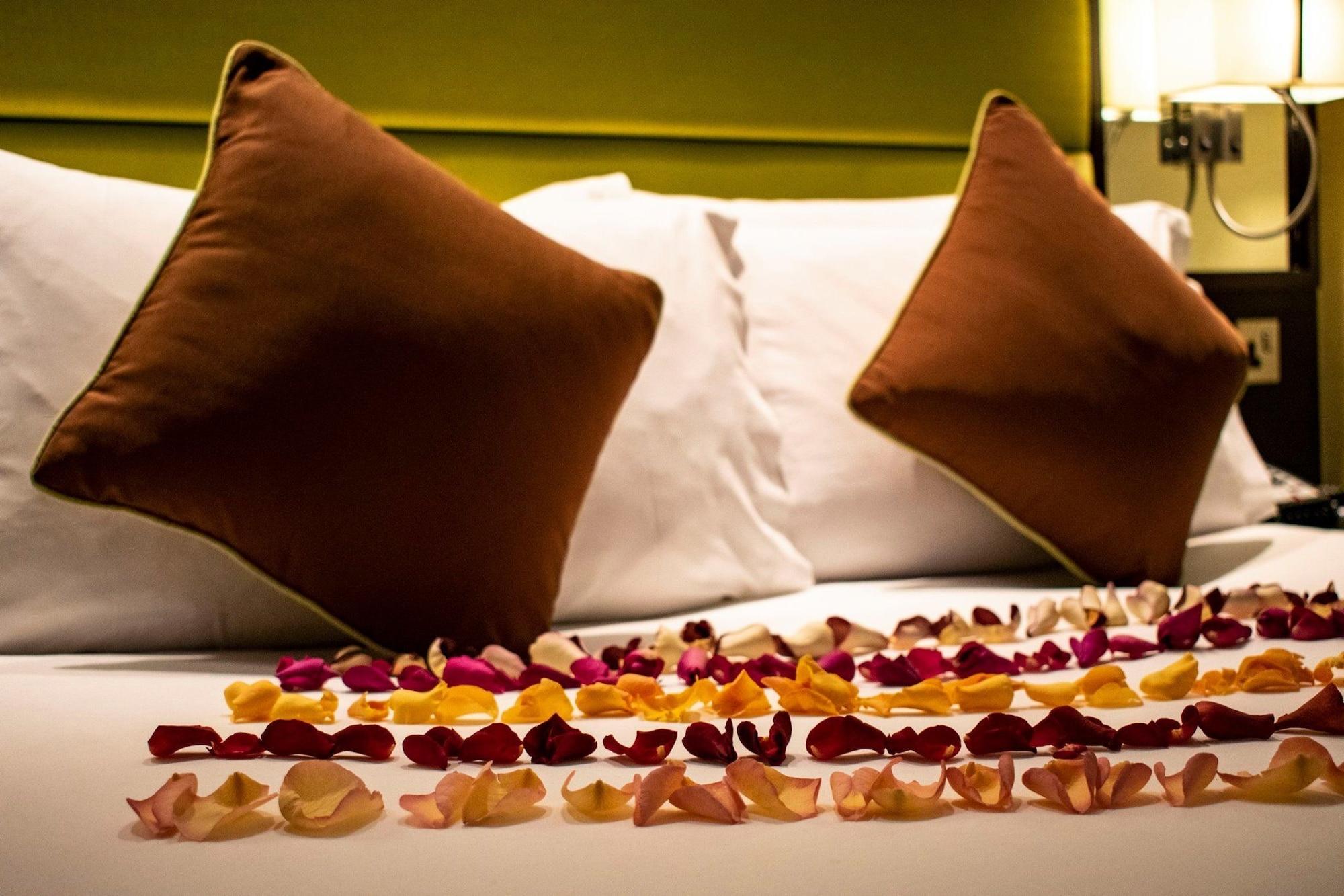 Montcalm Brewery Townhouse Hotel Londen Buitenkant foto The photo shows a neatly arranged bed with two white pillows and brown decorative cushions. Scattered across the bed is a decorative display of flower petals in various colors, including pink, yellow, and orange, creating a romantic or tranquil ambia