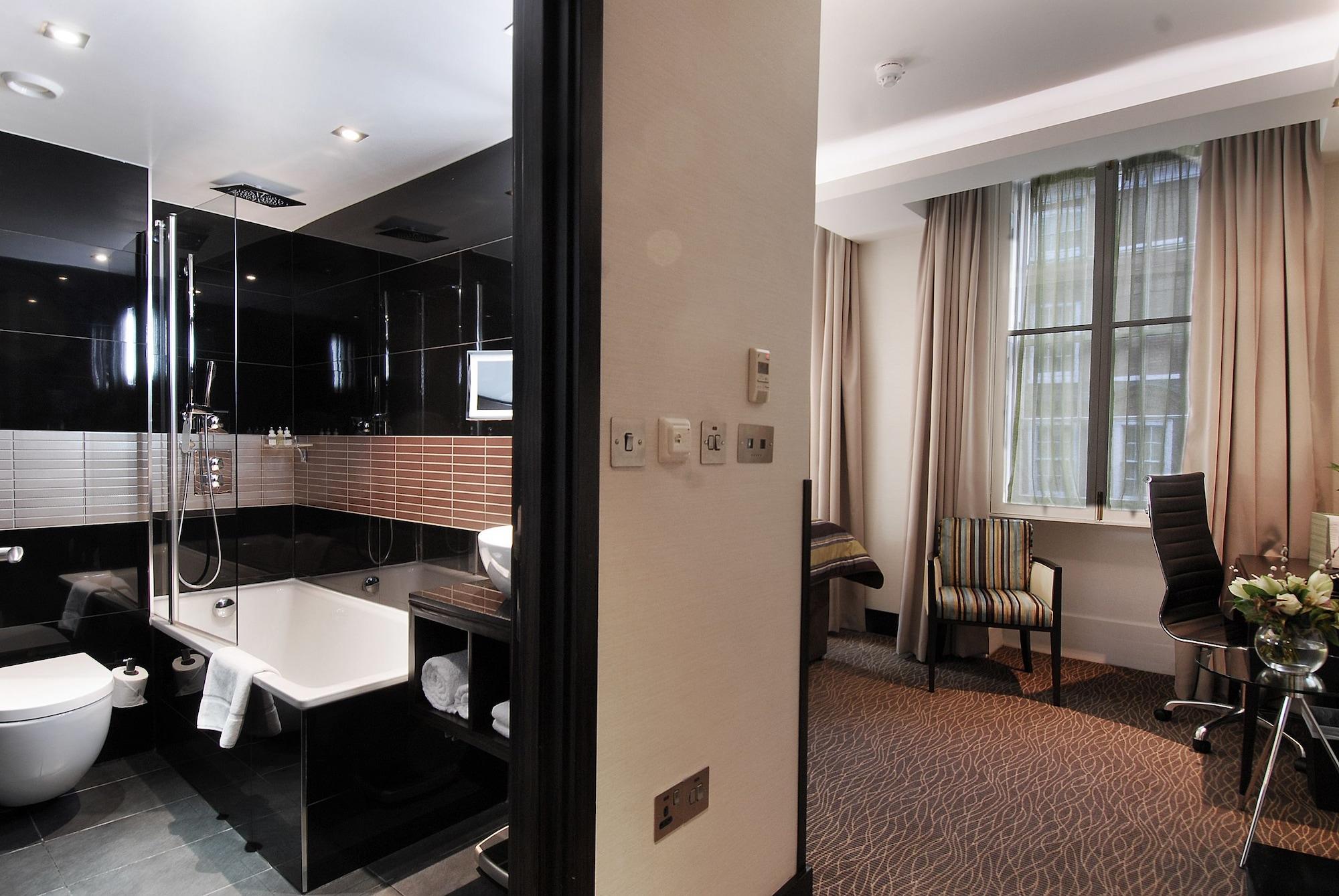 Montcalm Brewery Townhouse Hotel Londen Buitenkant foto The photo shows a modern hotel room that features an elegant bathroom on one side and a living area on the other. 

1. **Bathroom**: The bathroom is stylishly designed with a combination of black and white tiles. It includes a bathtub, a shower area 