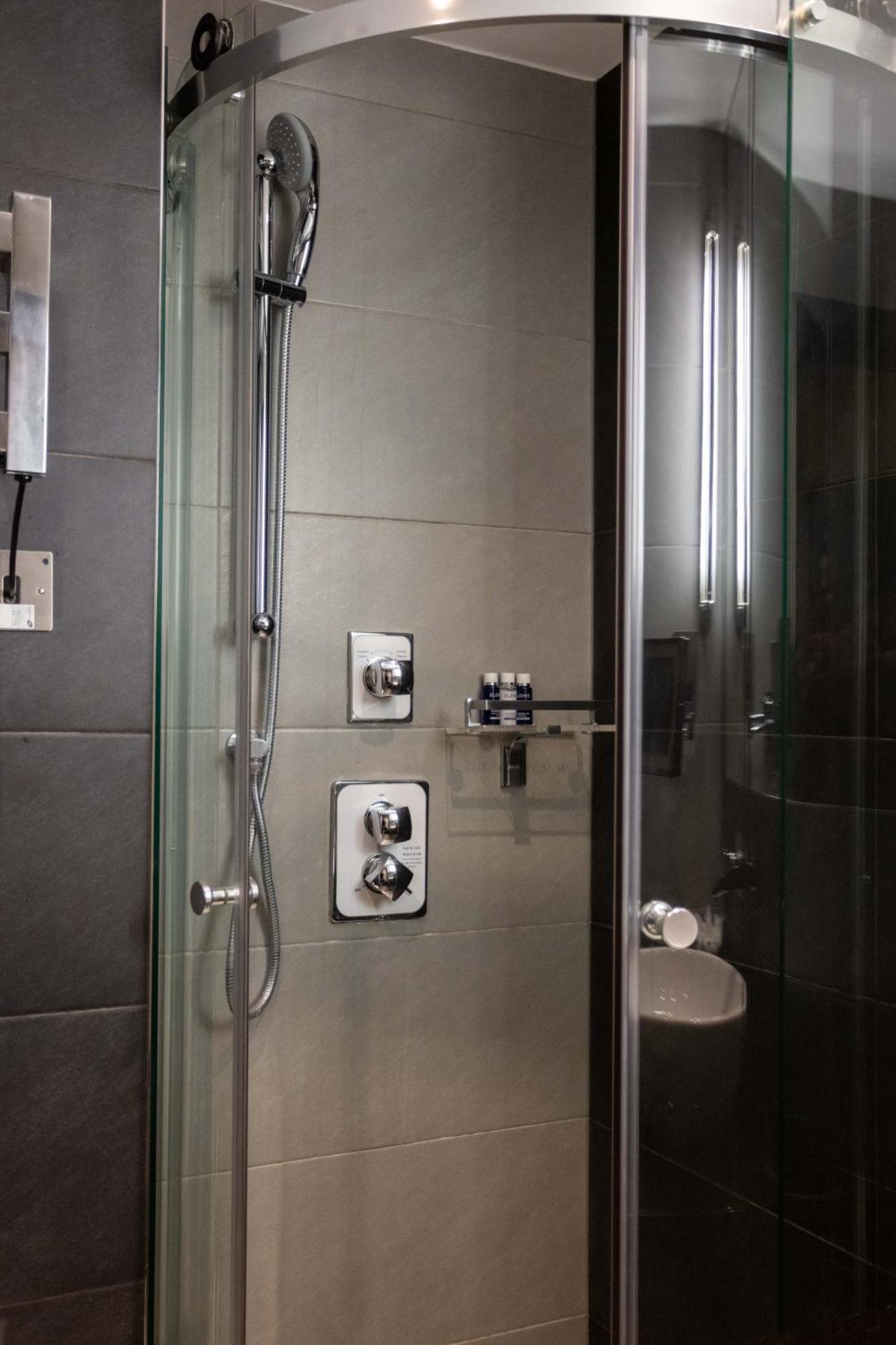 Montcalm Brewery Townhouse Hotel Londen Buitenkant foto The photo shows a modern shower area. It features glass panels and tiled walls in a neutral color palette, creating a sleek and contemporary look. There are two main control panels for adjusting the water temperature and pressure, with various knobs 