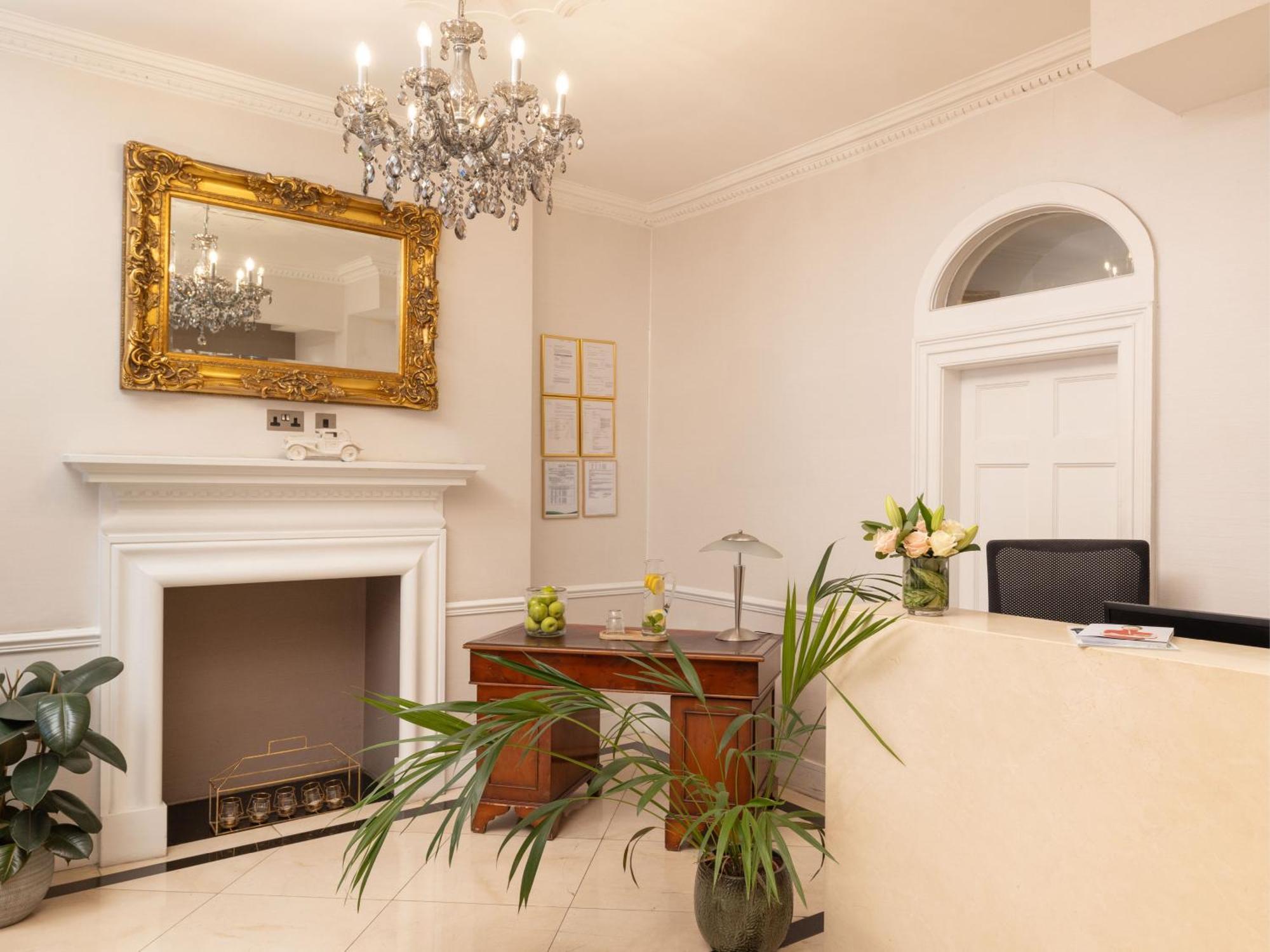 Montcalm Brewery Townhouse Hotel Londen Buitenkant foto The photo shows a stylish reception area. There is a decorative chandelier hanging from the ceiling, providing elegant lighting. A large, ornate mirror is mounted on the wall beside the fireplace, which features a simple, classic design. In front of 