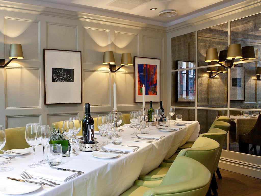Montcalm Brewery Townhouse Hotel Londen Buitenkant foto The photo shows an elegant restaurant setting with a long dining table that is neatly set for a meal. The table is adorned with a white tablecloth, glassware, and silverware, indicating that it is prepared for a special gathering or event. 

Behind t