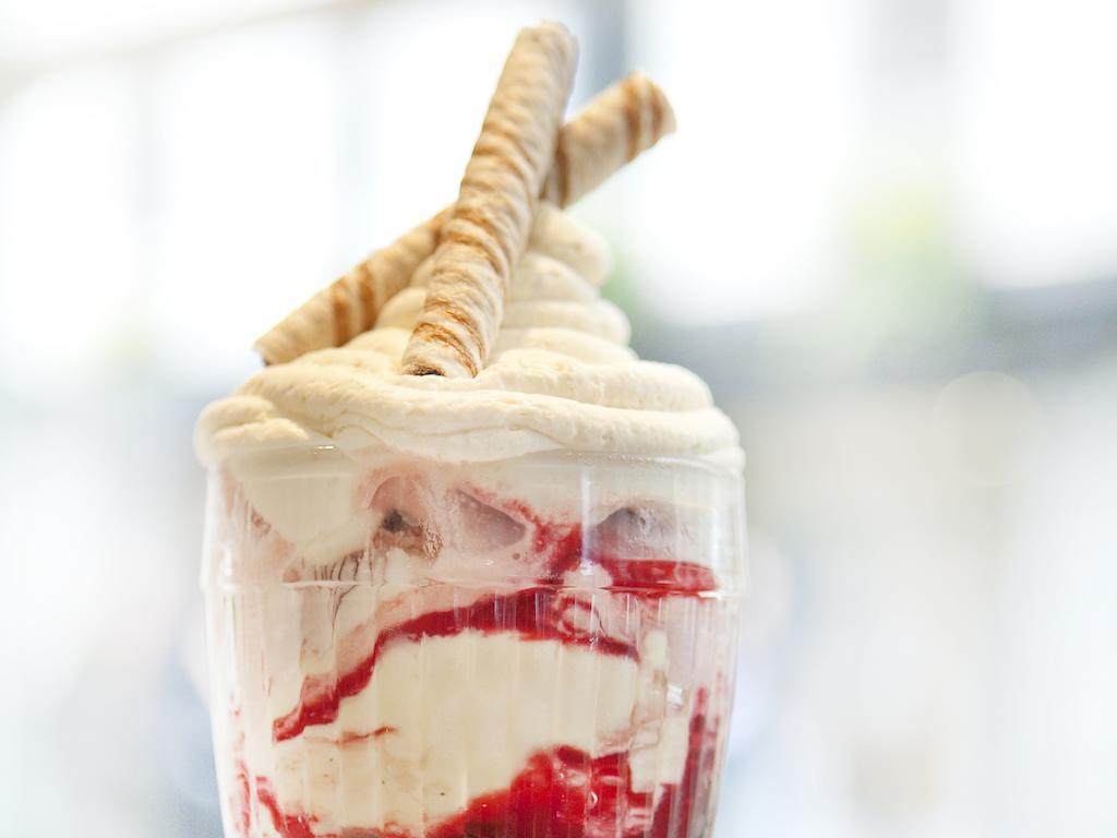 Montcalm Brewery Townhouse Hotel Londen Buitenkant foto The photo shows a delicious dessert in a clear glass dish. It features layers of creamy ice cream or whipped cream, swirled with a vibrant red fruit sauce. Topping the dessert are two rolled wafer sticks, adding a decorative touch. The overall presen