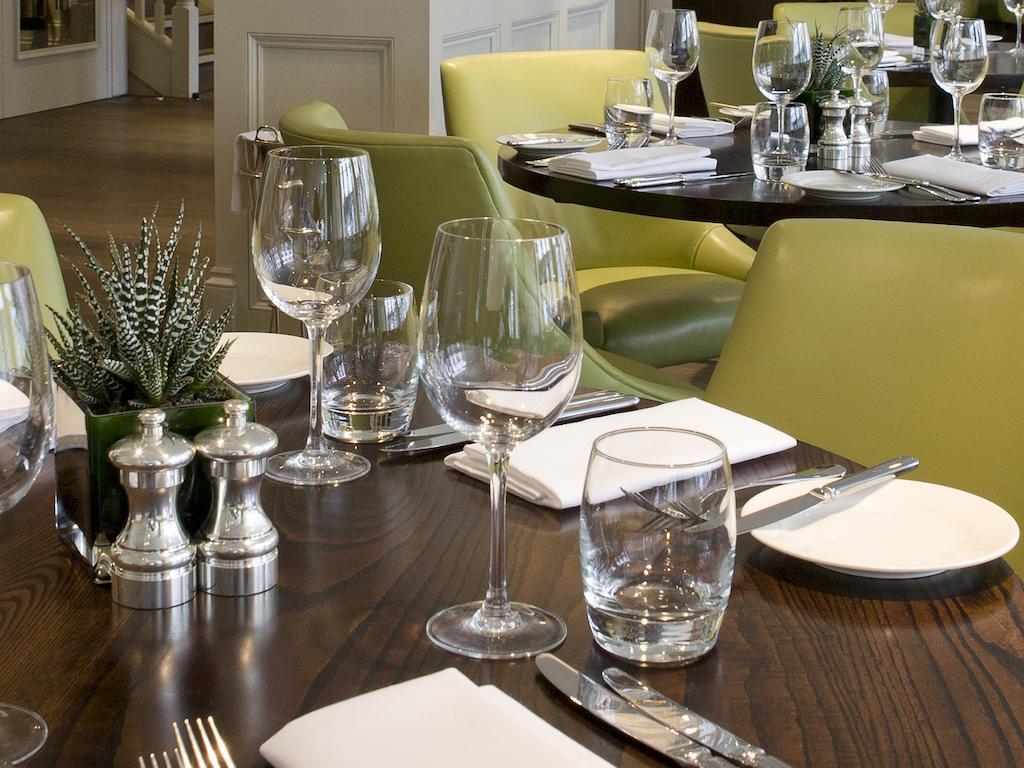 Montcalm Brewery Townhouse Hotel Londen Buitenkant foto The photo shows a dining setup in a restaurant. There are tables with a polished wooden surface and elegant place settings. Each setting includes multiple wine glasses and water glasses, neatly arranged with folded napkins. 

In the center, there are