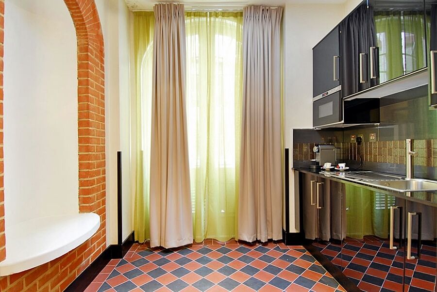 Montcalm Brewery Townhouse Hotel Londen Buitenkant foto The photo shows a kitchen area with modern design elements. There are large, light-colored curtains hanging from the windows, allowing natural light to filter in. The walls are partially exposed brick, giving a warm texture to the room. The flooring 