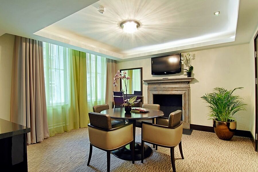 Montcalm Brewery Townhouse Hotel Londen Buitenkant foto The photo shows a well-furnished room, likely a hotel suite or a modern living space. It features a round dining table with four comfortable chairs. The walls are adorned with light-colored decor, and there are large windows with sheer and solid curt
